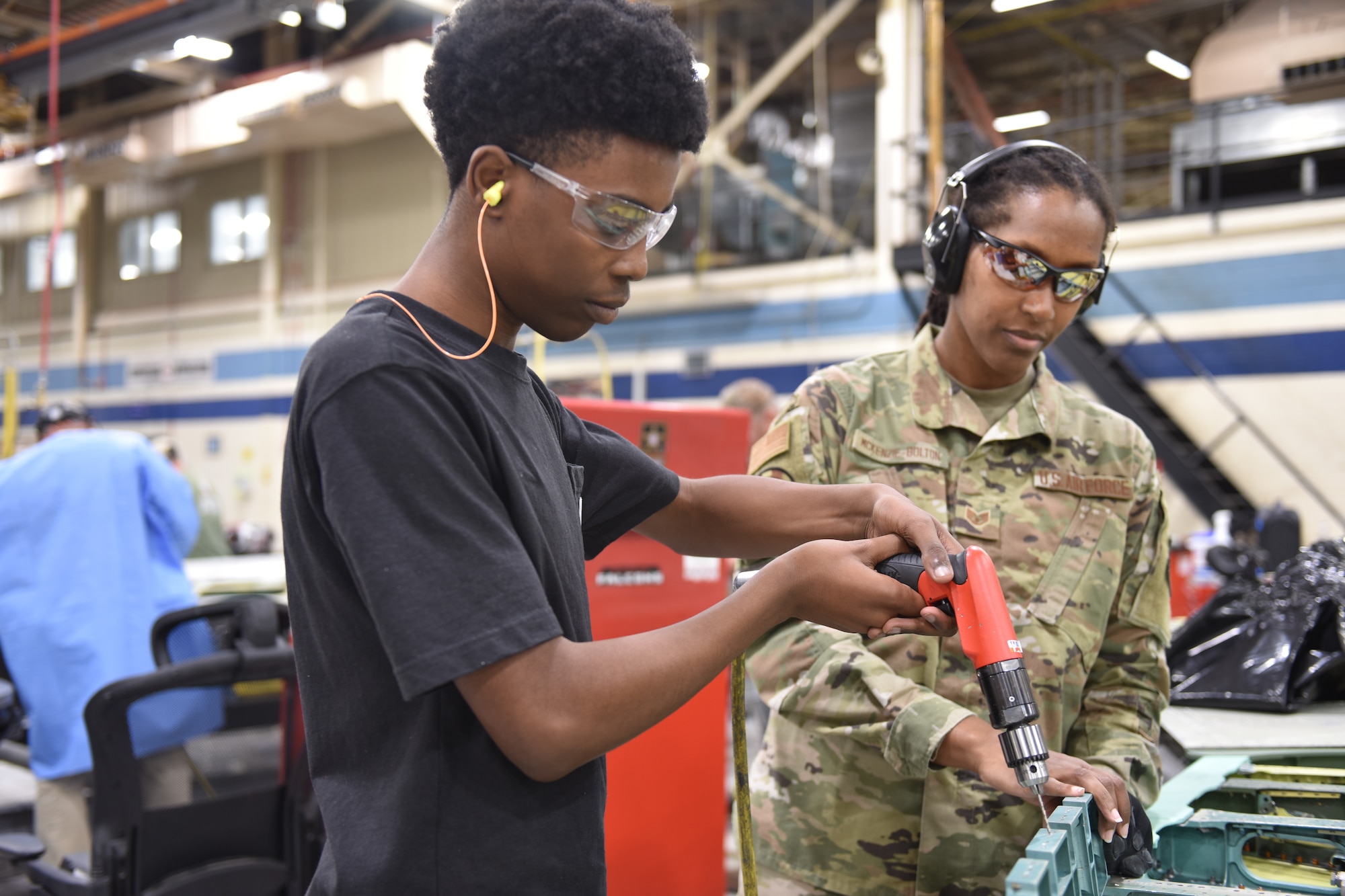 Man holding a power tool while working on an aircraft part