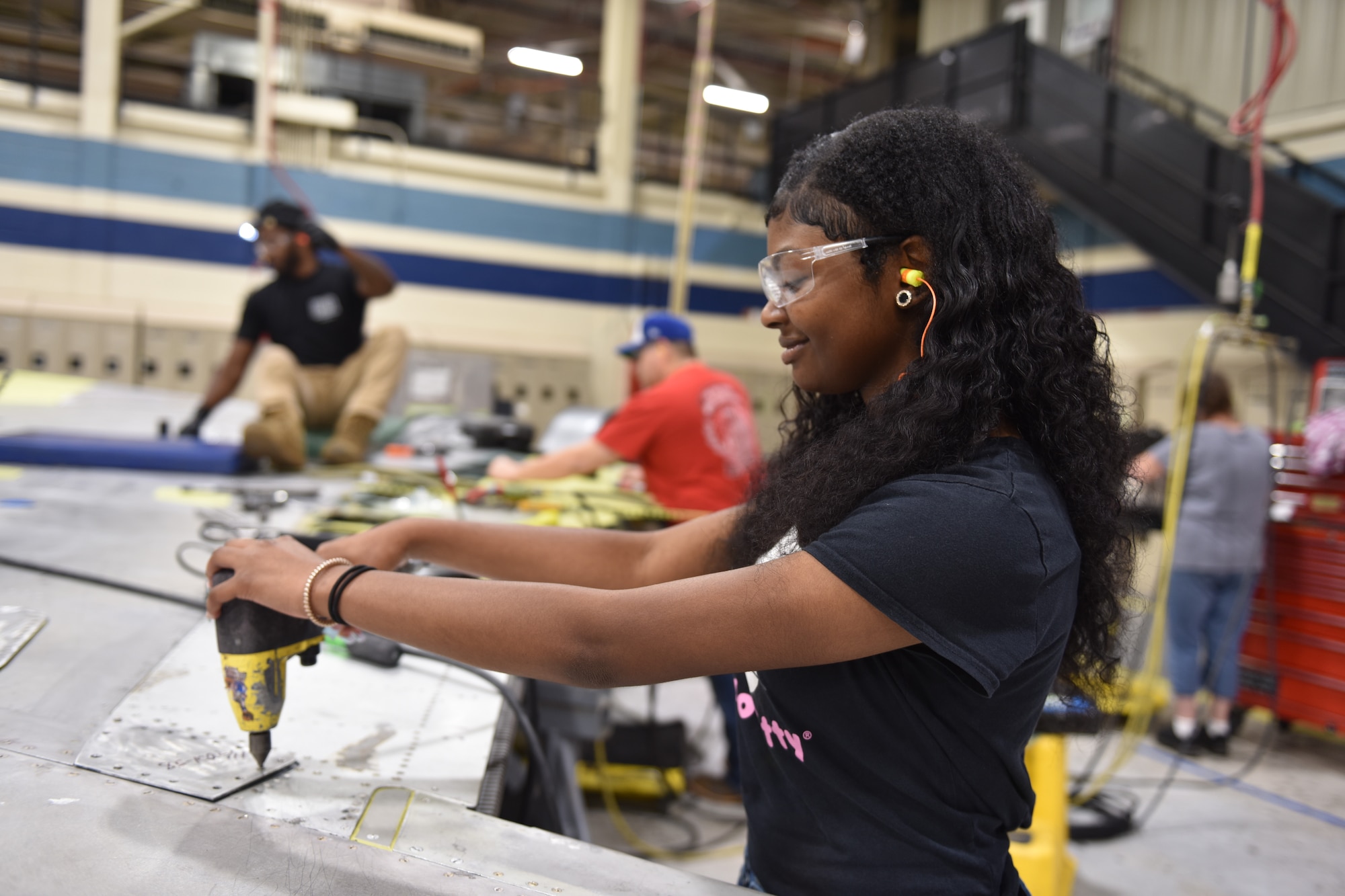 Woman holding a power tool while working on an aircraft part