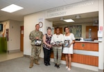 Shannon Feaster poses with a photo, and personalized legacy project kit, of her late 8-year-old daughter Savi Redman alongside the pediatric oncology care team during a visit to Walter Reed National Military Medical Center on July 18, 2024. (DOD photo by Christian Lilakos)