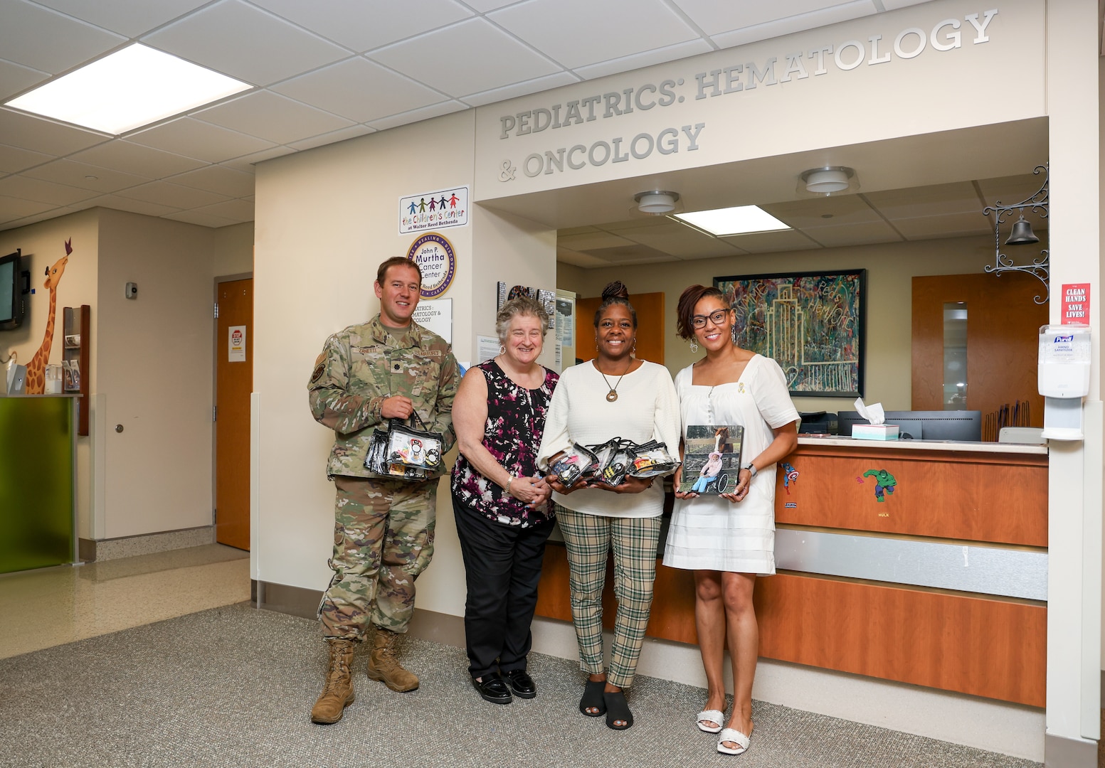 Shannon Feaster poses with a photo, and personalized legacy project kit, of her late 8-year-old daughter Savi Redman alongside the pediatric oncology care team during a visit to Walter Reed National Military Medical Center on July 18, 2024. (DOD photo by Christian Lilakos)