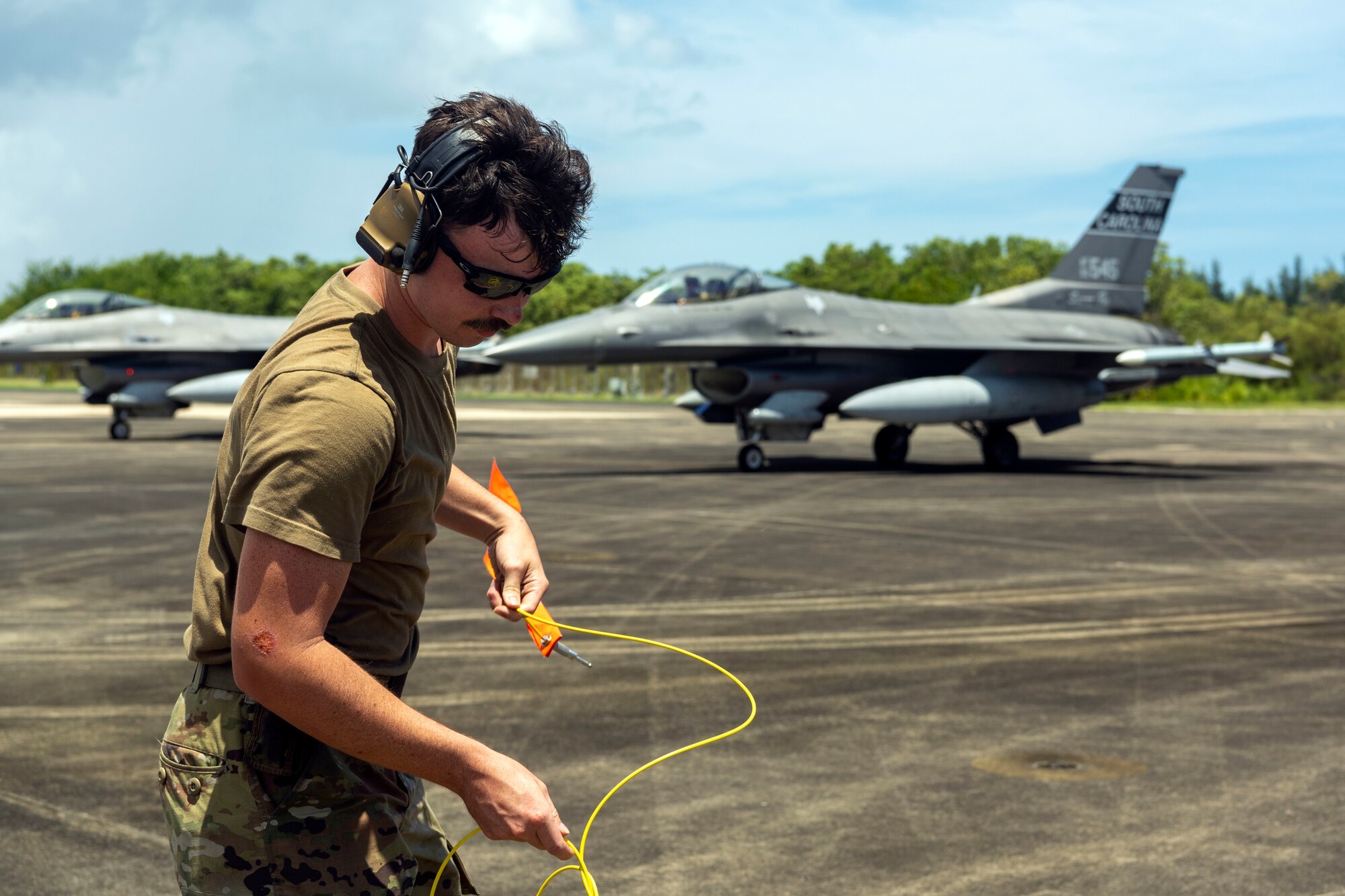 A U.S. Airman assigned to the 169th Aircraft Maintenance Squadron, South Carolina Air National Guard, prepares to set a ground cable during exercise Caribbean Fox at Muñiz Air National Guard Base, Carolina, Puerto Rico, July 23, 2024. Caribbean Fox is designed to challenge participants in dynamic training scenarios during a two-week period along with offering tailored training for accomplishing critical Agile Combat Employment (ACE) readiness requirements. (U.S. Air National Guard photo by Airman 1st Class Gisselle Toro Caraballo)