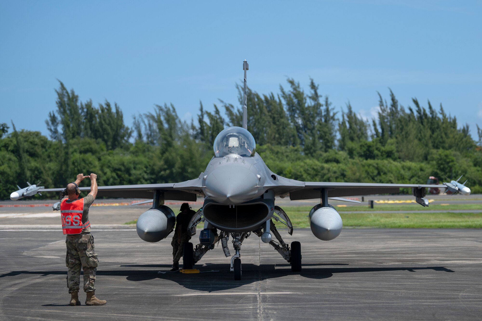 A U.S. Airman with the 169th Aircraft Maintenance Squadron, South Carolina Air National Guard, marshals an F-16 Fighting Falcon fighter jet assigned to the 169th Fighter Wing during exercise Caribbean Fox at Muñiz Air National Guard Base, Carolina, Puerto Rico, July 23, 2024. Caribbean Fox is designed to challenge participants in dynamic training scenarios during a two-week period along with offering tailored training for accomplishing critical Agile Combat Employment (ACE) readiness requirements. (U.S. Air National Guard photo by Airman 1st Class Victoria A. Jewett)