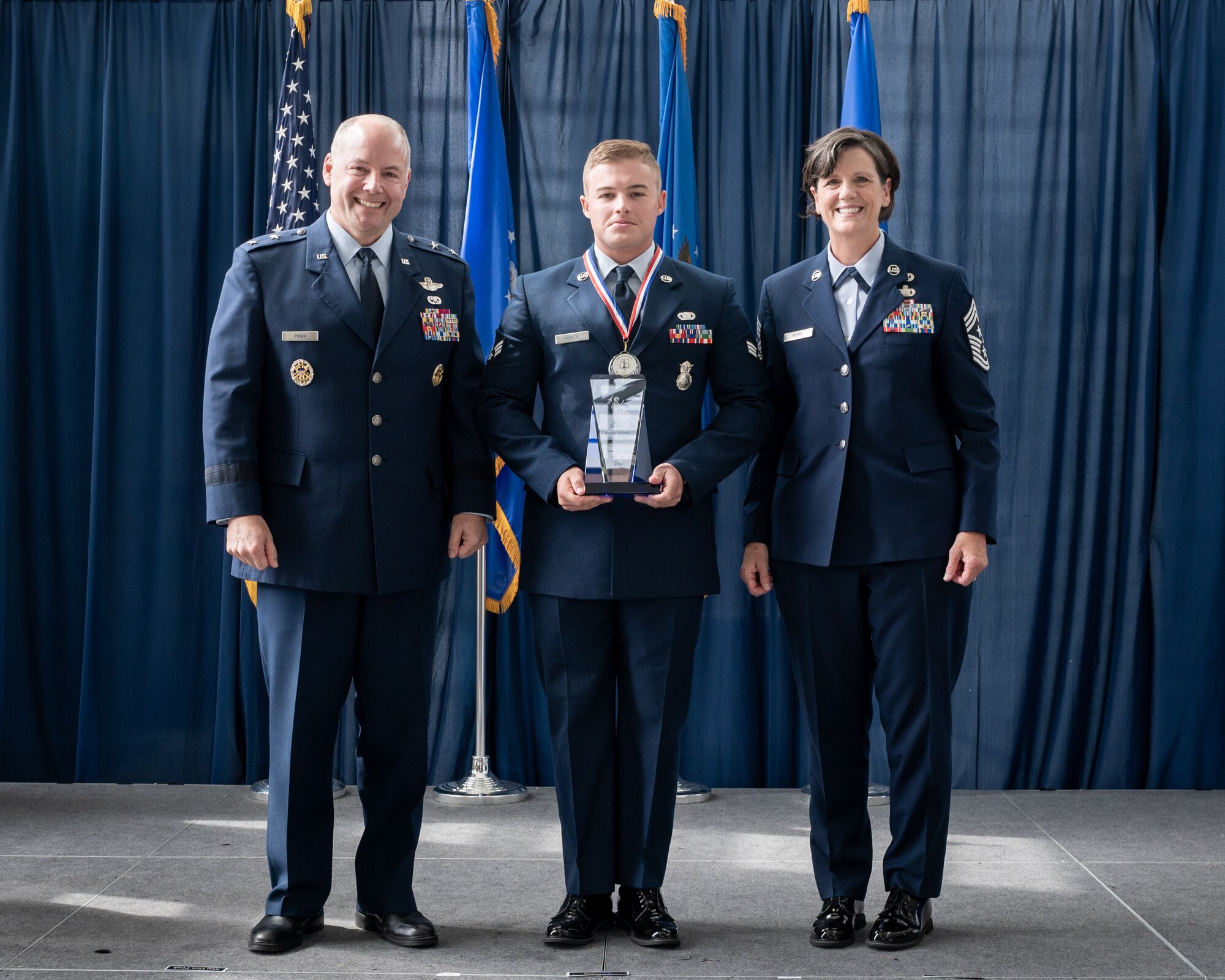U.S. Air Force Senior Airman Gavin Woken, a Security Forces  Airman for the 121st Air Refueling Wing, Ohio National Guard poses with Maj. Gen. Duke Pirak, left, acting director, Air National Guard, and Chief Master Sgt. Lisa Perry, interim command chief, ANG, after being recognized as the Outstanding Airman of the Year during a ceremony at the Air National Guard Readiness Center, Joint Base Andrews, Maryland, July 26, 2024. The ceremony was part of Focus on the Force Week 2024—an annual, week-long event hosted by Air National Guard senior enlisted leadership designed to highlight professional development and honor the achievements of the enlisted corps’ top performing members. (U.S. Air National Guard photo by Master Sgt. Brandy Fowler)