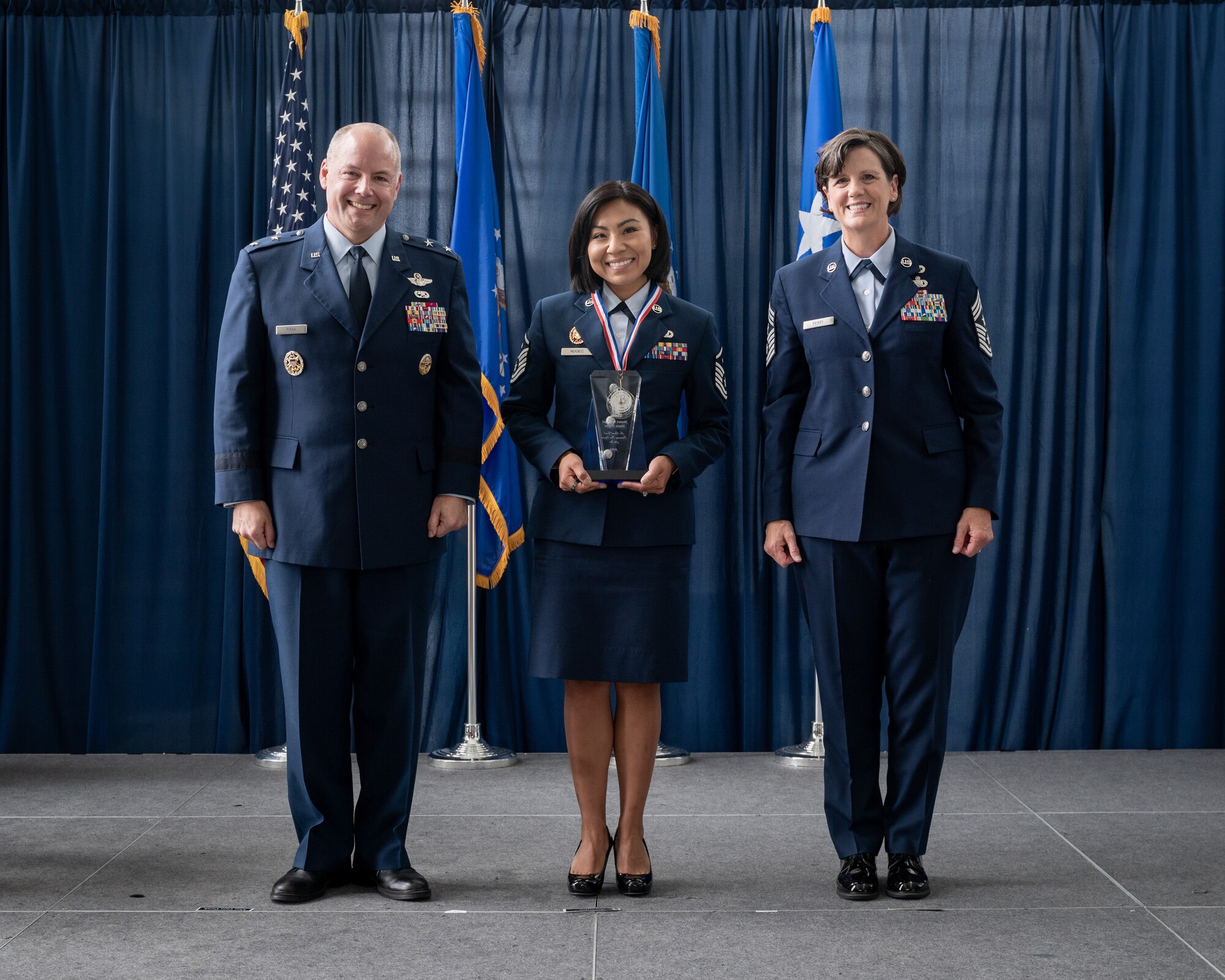 U.S. Air Force Master Sgt. Diana Nogiec, a first sergeant for the 110th Wing, Michigan National Guard poses with Maj. Gen. Duke Pirak, left, acting director, Air National Guard and Chief Master Sgt. Lisa Perry, interim command chief, ANG, after being recognized as the First Sergeant of the Year during a ceremony at the Air National Guard Readiness Center, Joint Base Andrews, Maryland, July 26, 2024. The ceremony was part of Focus on the Force Week 2024—an annual, week-long event hosted by Air National Guard senior enlisted leadership designed to highlight professional development and honor the achievements of the enlisted corps’ top performing members. (U.S. Air National Guard photo by Master Sgt. Brandy Fowler)