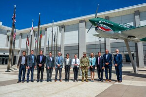 A group of Aerospace company leaders stand with a US Space Force General in front of a building.