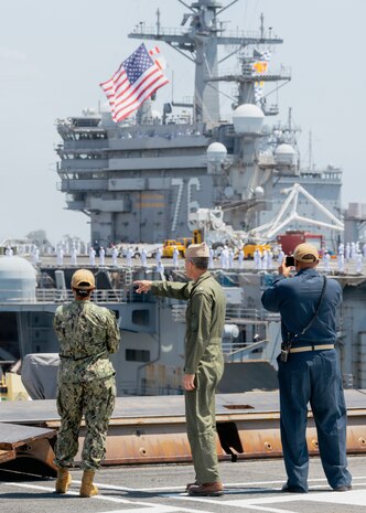 Rear Adm. Greg Newkirk, center, commander of Task Force 70 and Carrier Strike Group 5, observes Nimitz-class aircraft carrier USS Ronald Reagan (CVN 76) moor from the flight deck of Nimitz-class aircraft carrier USS George Washington (CVN 73) while pierside on Naval Air Station North Island, San Diego July 23, 2024.