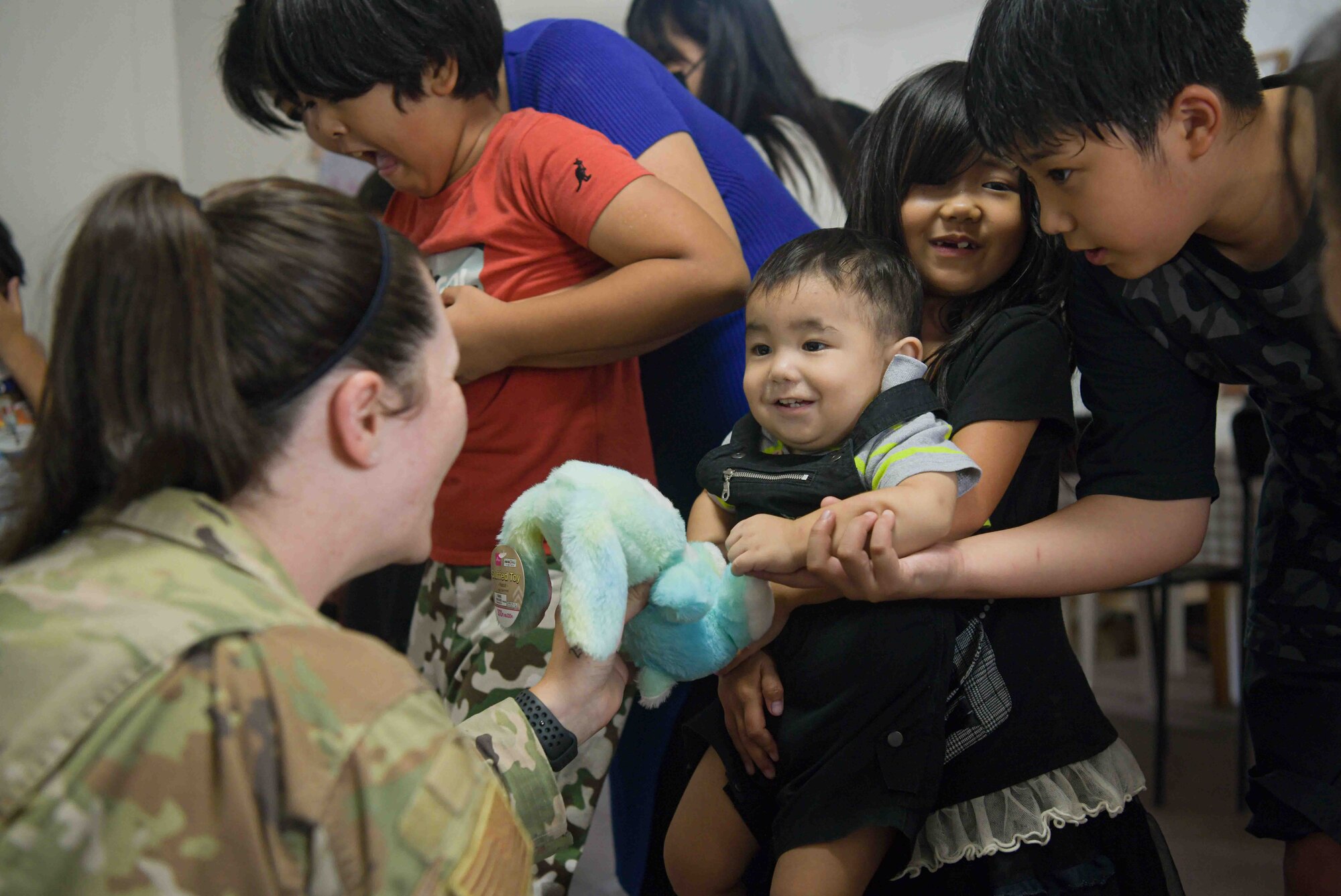 U.S. Air Force Tech. Sgt. Brittany Sampson, 353rd Special Operations Wing,  occupational safety manager plays with a toddler during a Christmas in July event at a child support facility outside Kadena Air Base, Japan, July 23, 2024.