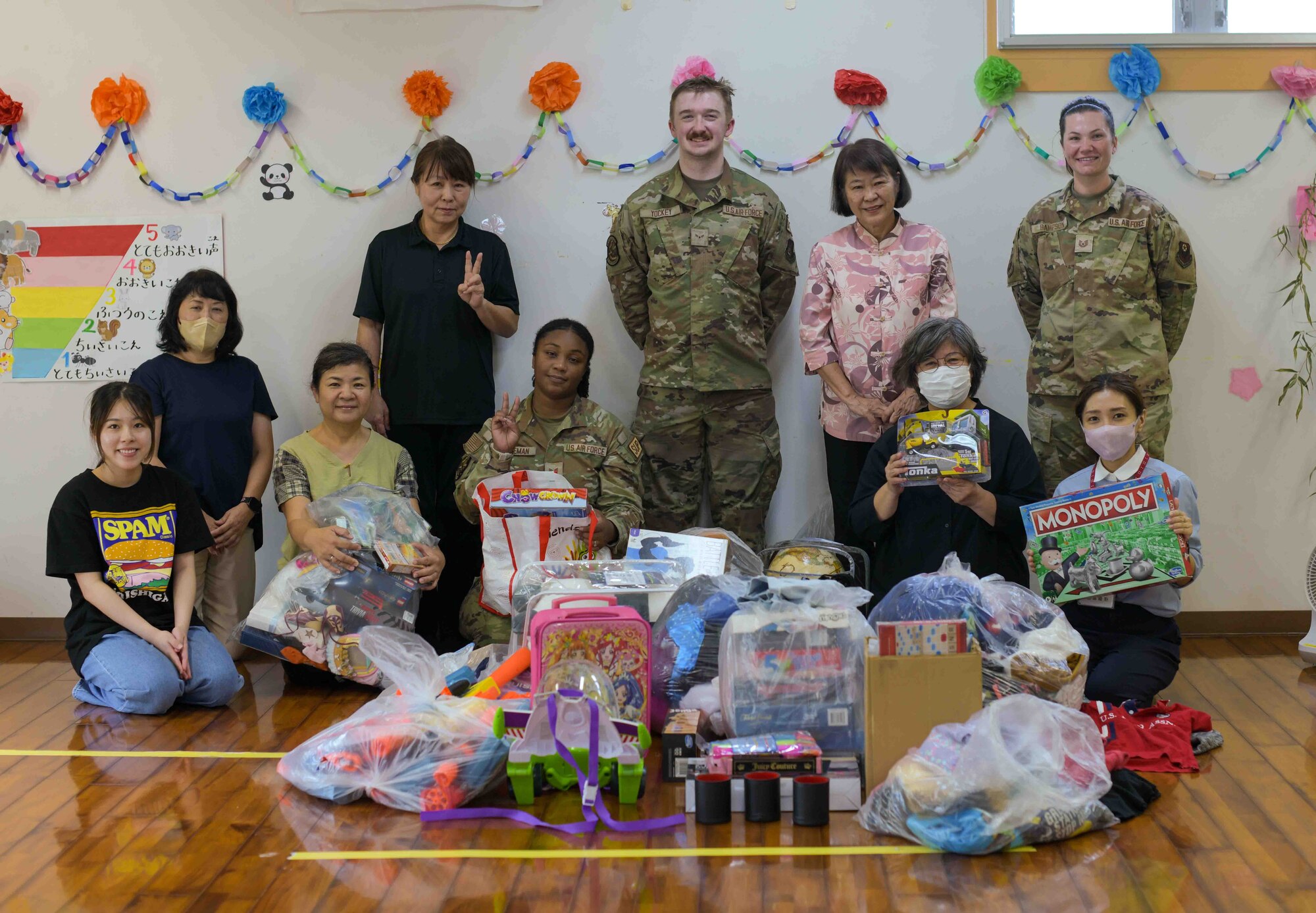 U.S. Air Force Airmen with the 18th Wing and 353rd Special Operations Wing and children’s support facility staff members pose for a group photo during a Christmas in July event at a child support facility outside Kadena Air Base, Japan, July 23, 2024.