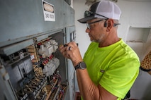an electrician performs maintenance on an electrical panel