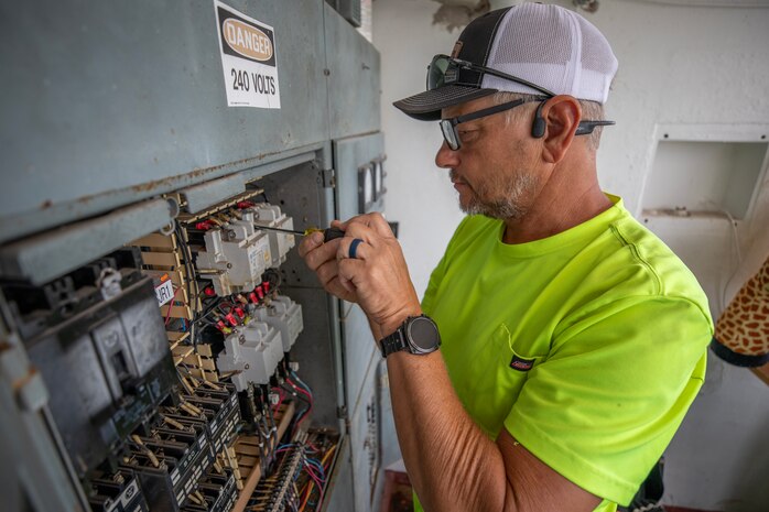 an electrician performs maintenance on an electrical panel
