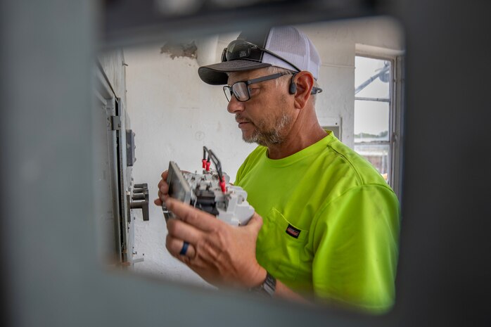 an electrician performs maintenance on an electrical panel