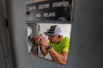 an electrician performs maintenance on an electrical panel