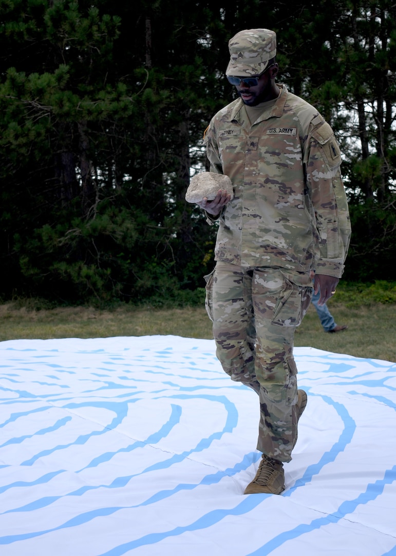 Photo of Soldier Recovery Unit Soldier walking labyrinth while holding a rock.