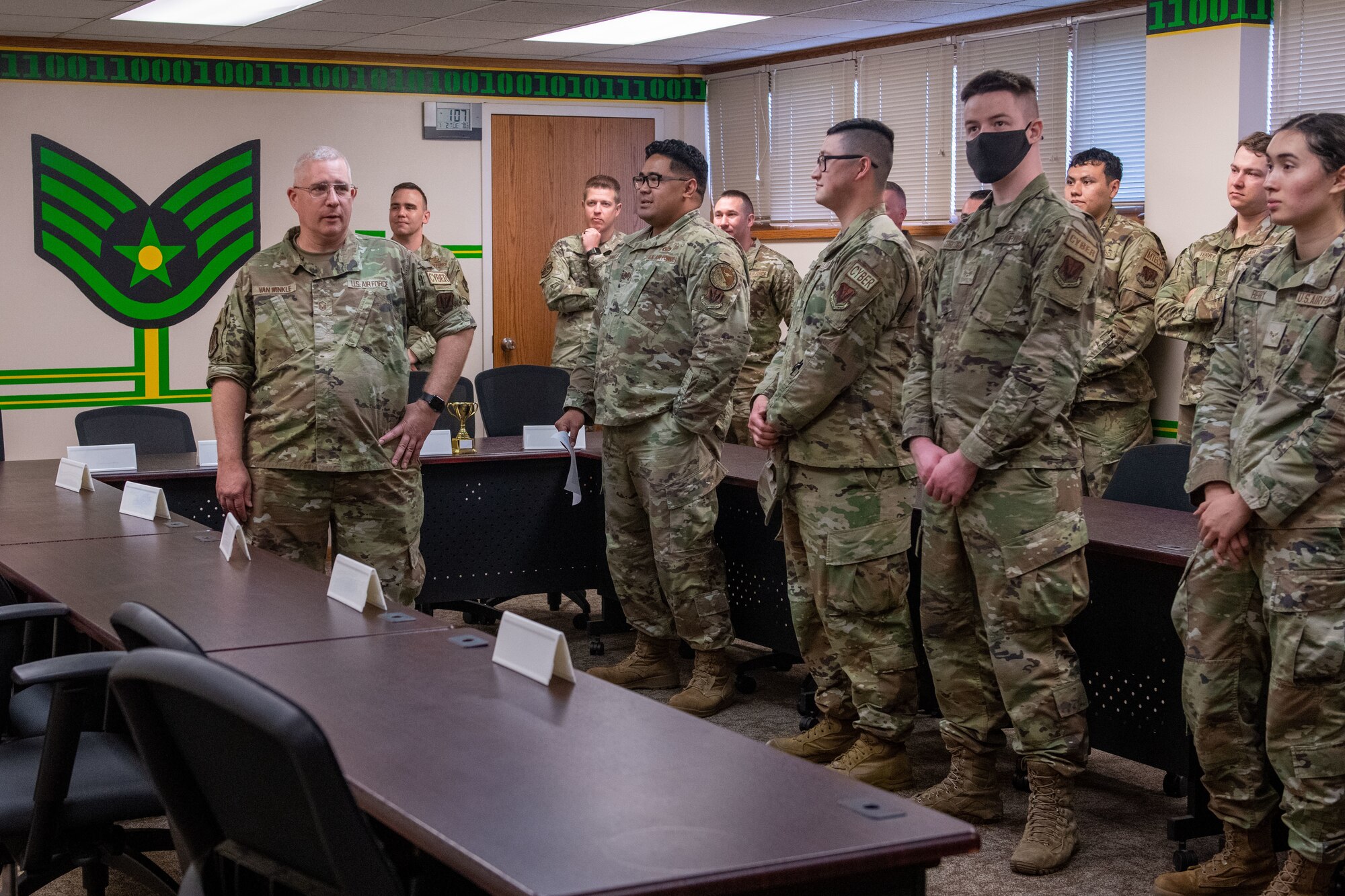 Airmen stand in a line in front of a crowd of airmen.