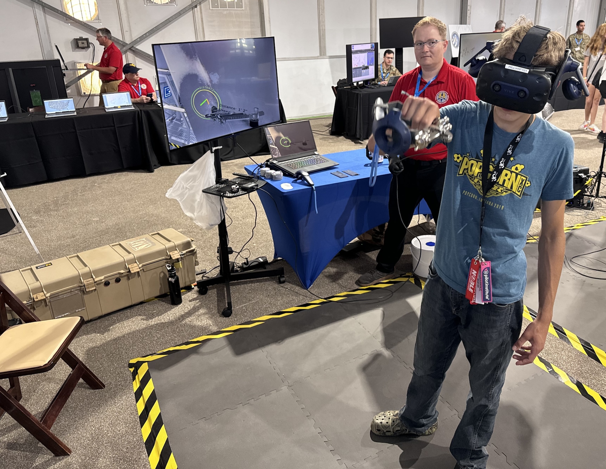 Andrew D. Orme, a mechanical engineer with the 309th Aviation Maintenance Group out of Hill Air Force Base, Utah, observes as an AirVenture attendee uses as a virtual reality paint trainer to simulate painting the tail of a C-5 Galaxy, July 22.