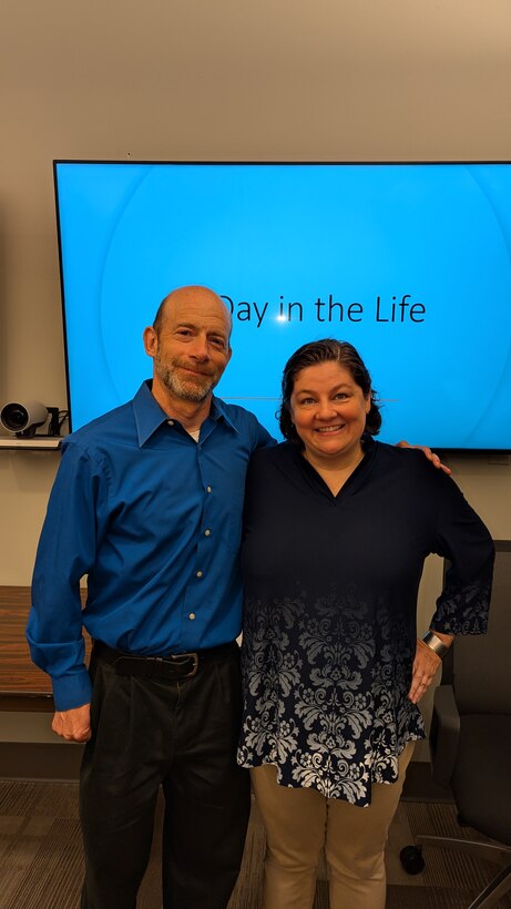 man and woman smile in front of presentation