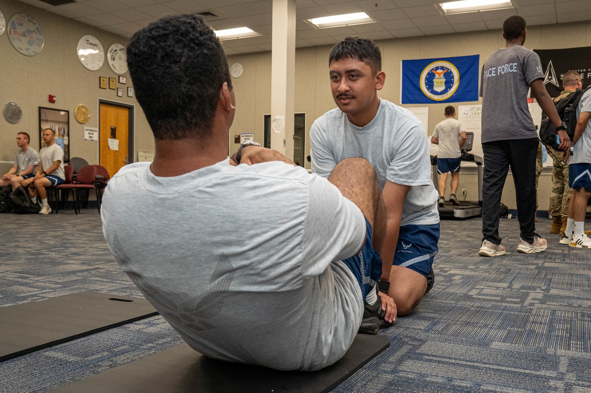 U.S. Air Force Airman 1st Class Raymond Brown, 338th Training Squadron student, helps Airman 1st Class Braxton Corbie, 338th TRS student, perform sit-ups during the Student Health Fair on Keesler Air Force Base, July 19, 2024.