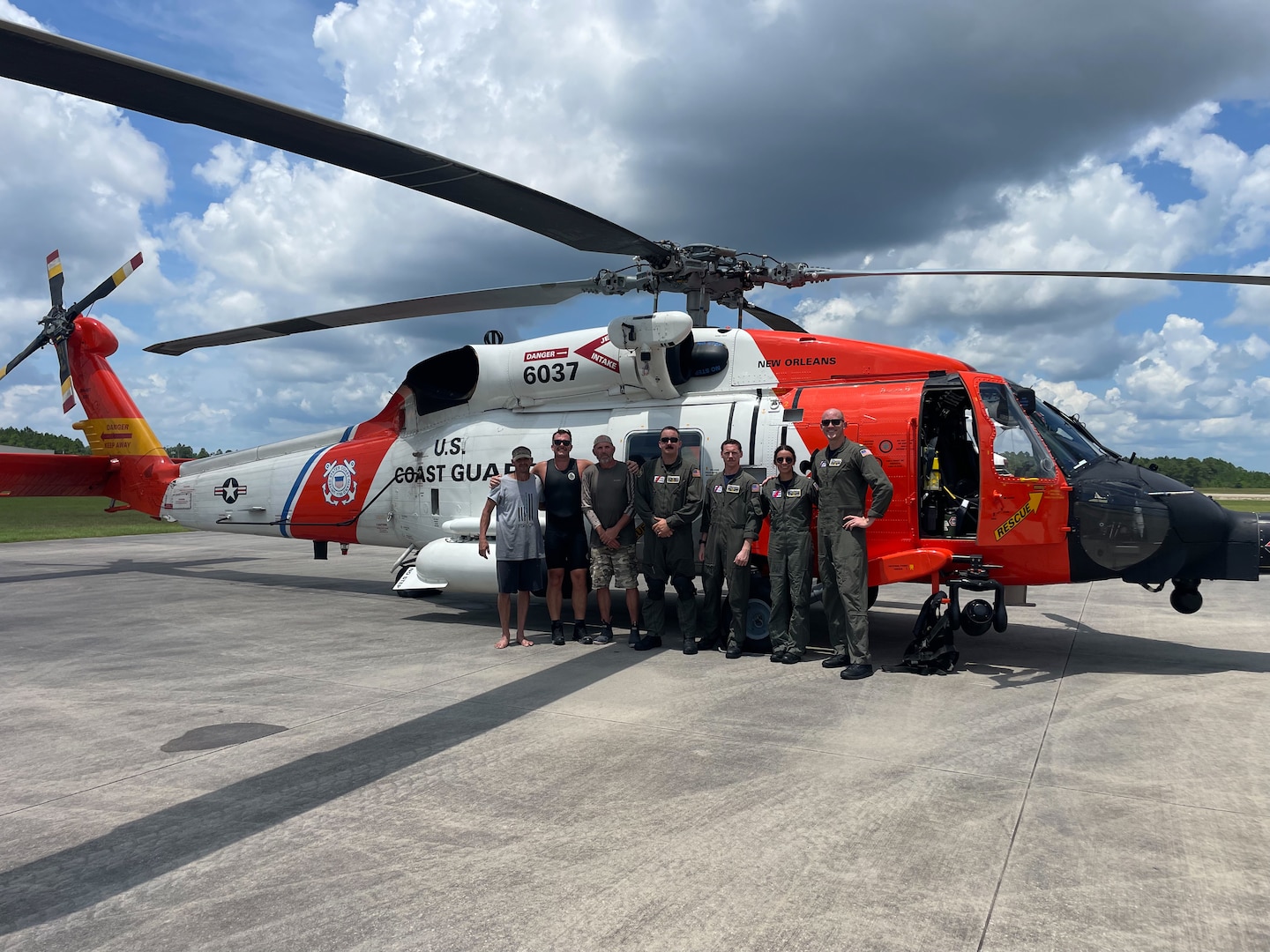 A Coast Guard Air Station New Orleans MH-60 Jayhawk helicopter aircrew and two rescued boaters stand in front of a MH-60 Jayhawk helicopter July 29, 2024, near Gulfport, Mississippi. The two boaters were stranded overnight on Horn Island in Mississippi before being rescued by the Coast Guard. (U.S. Coast Guard video courtesy Air Station New Orleans)