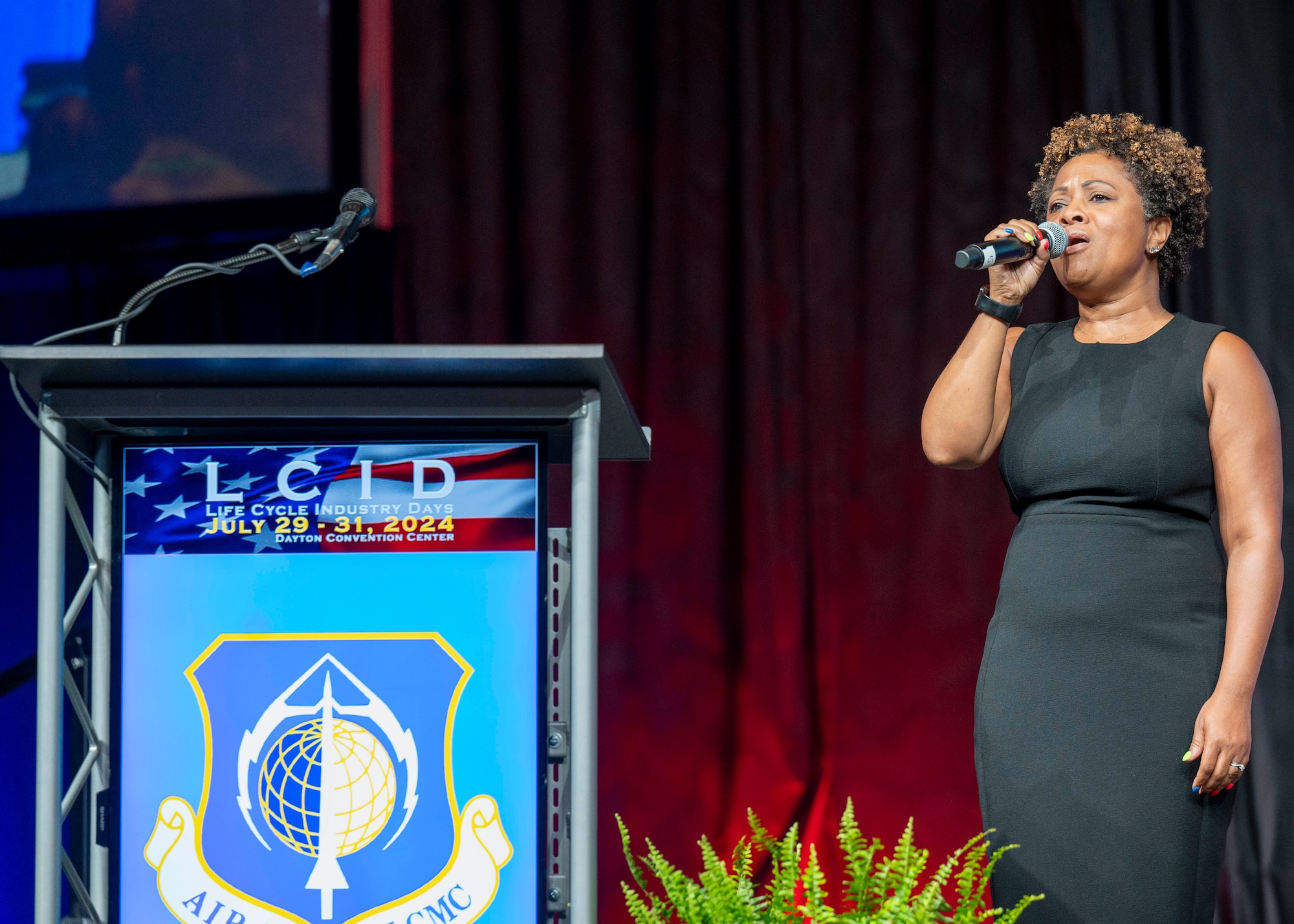 Woman in black dress with microphone on stage.