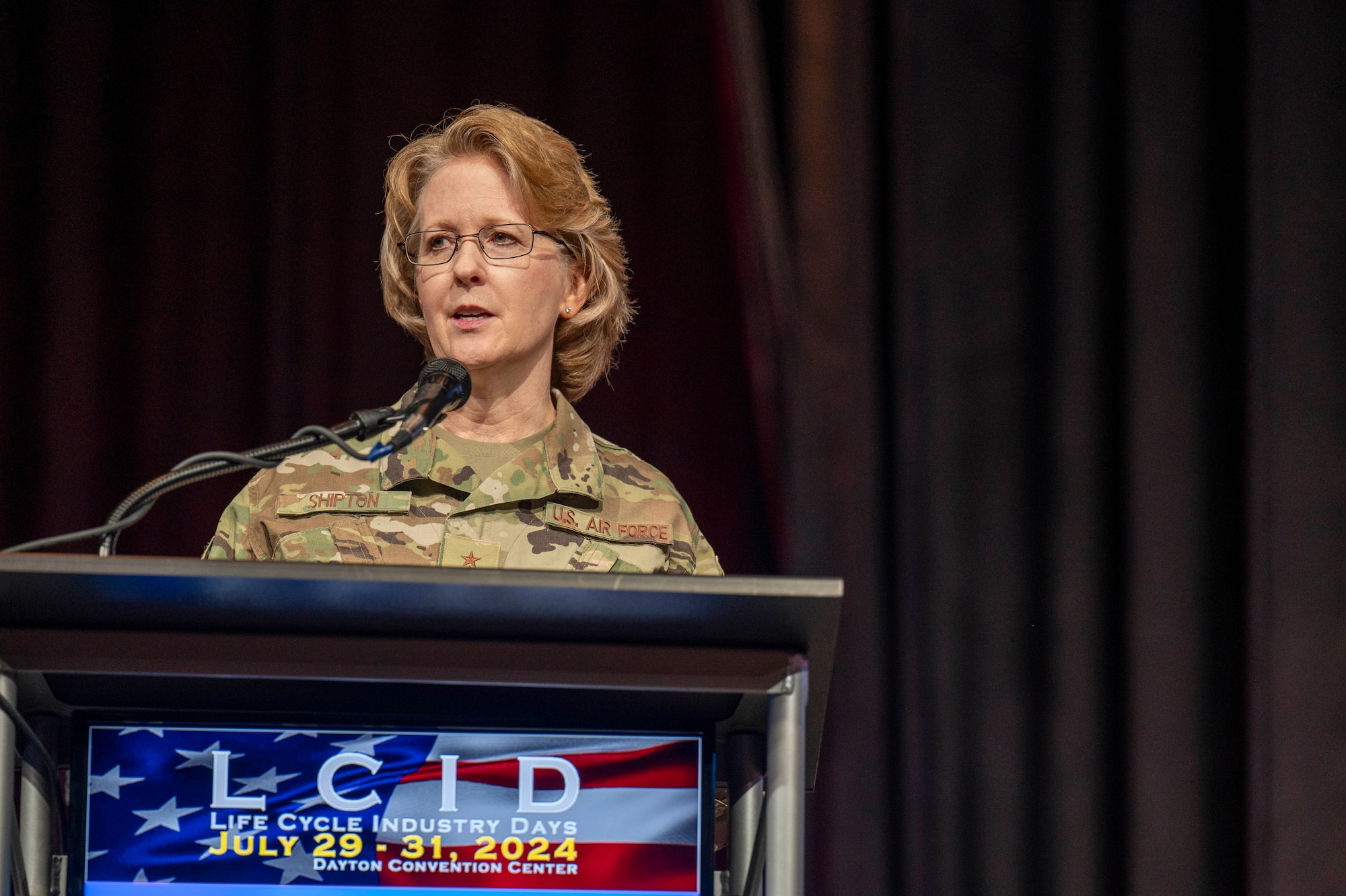 USAF female general speaks behind podium.