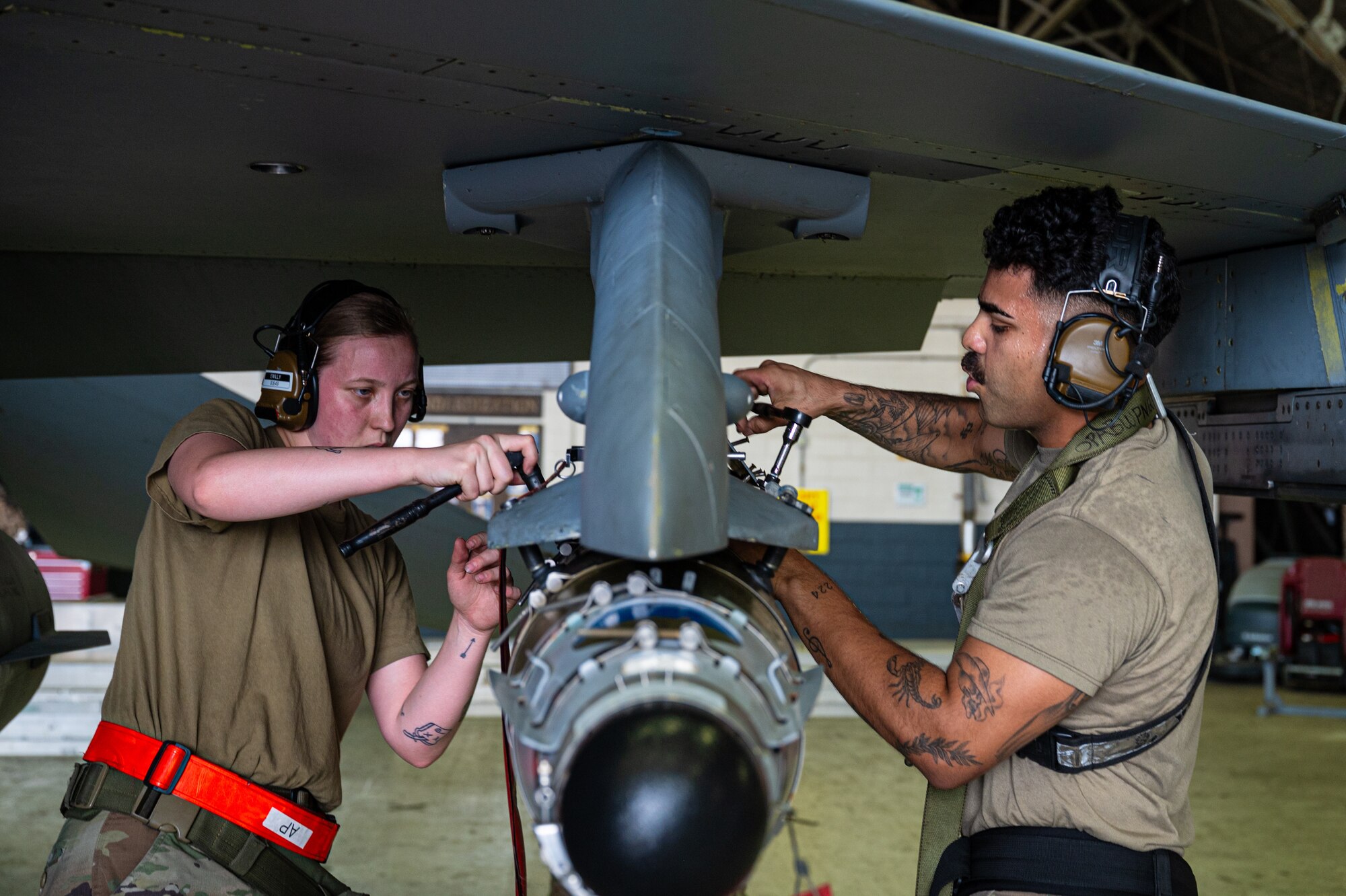 U.S. Air Force Staff Sgt. Jorge Aparicio, right, 36th Fighter Generation Squadron weapons load crew team chief, and Senior Airman Erin Williamson, left, weapons load crew member, load a munition onto an aircraft, during the 2nd Quarter Load Crew Competition at Osan Air Base, Republic of Korea, July 26, 2024. Load Crew Competitions promote a competitive environment, where Airmen display their skills and abilities enabling trust and capability to execute the mission. (U.S. Air Force photo by Staff Sgt. Christopher Tam)