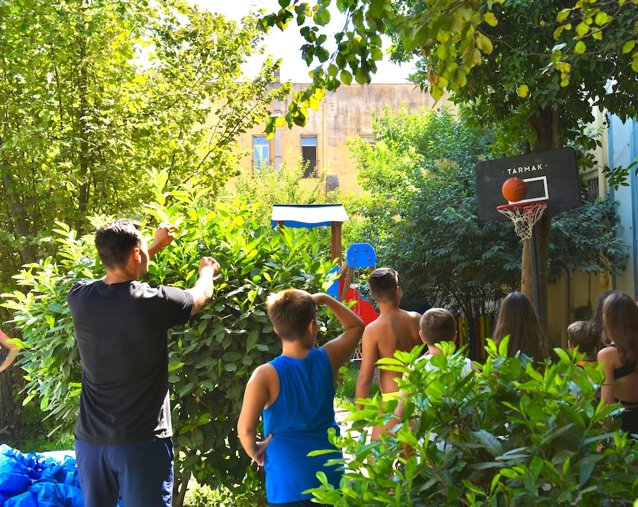 Petty Officer 1st Class Clarence Evans, assigned to U.S. Naval Support Activity (NSA) Naples engages in outdoor activities with children from the Associazione Gioventù Cattolica [Catholic Youth Association] during a community relations event to promote cross-culture interaction with inner-city youths in Naples, Italy, Jul. 19, 2024. The association provides family foster care, adoption services, environmental protection, and sports activities for youths living in an at-risk area as an effort to support the community’s vulnerable children. NSA Naples is an operational ashore base that enables U.S., allied, and partner nation forces to be where they are needed, when they are needed to ensure security and stability in Europe, Africa, and Southwest Asia. (U.S. Navy photo by Josephine Schneider)