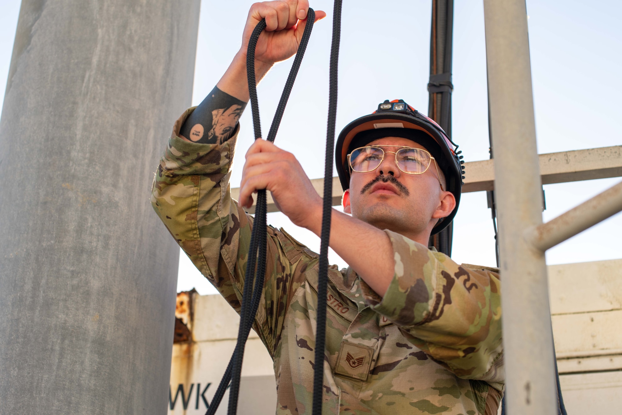 military member looks at rope sitting underneath a training tower