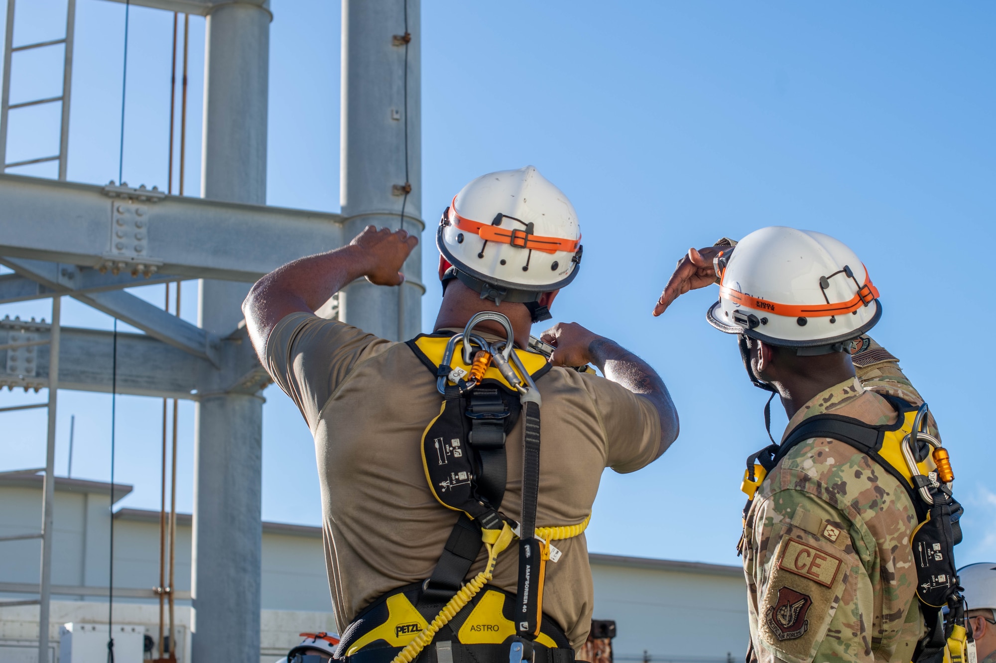 two military members look up at a tower
