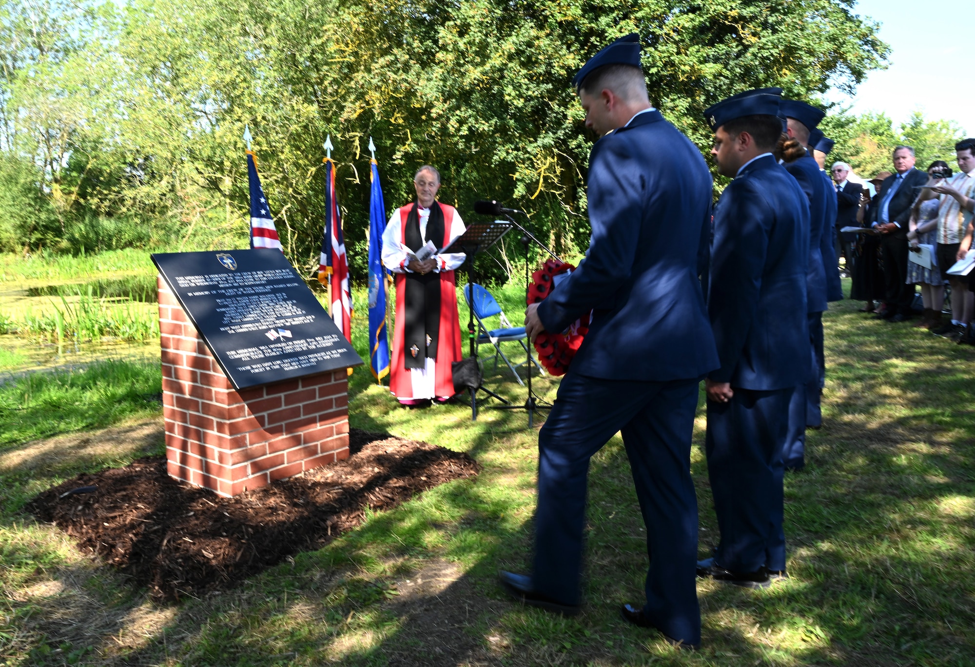 U.S. Air Force Airmen from Royal Air Force Mildenhall stand at attention in front of the flags as they prepare to lay a wreath and pay their respects at a memorial honoring the crew of a B-17 Flying Fortress, “Little Boy Blue,” at a ceremony near Bury St. Edmunds, Suffolk, England, July 19, 2024. The ceremony was held on the 80th anniversary of the crash, from which there were only two survivors, and family members of the crew attended the ceremony. (U.S. Air Force photo by Karen Abeyasekere)