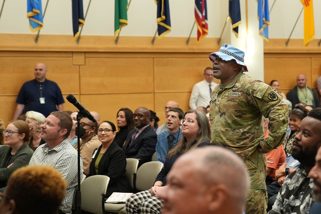 man in uniform walks through crowd in auditorium