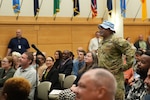 man in uniform walks through crowd in auditorium
