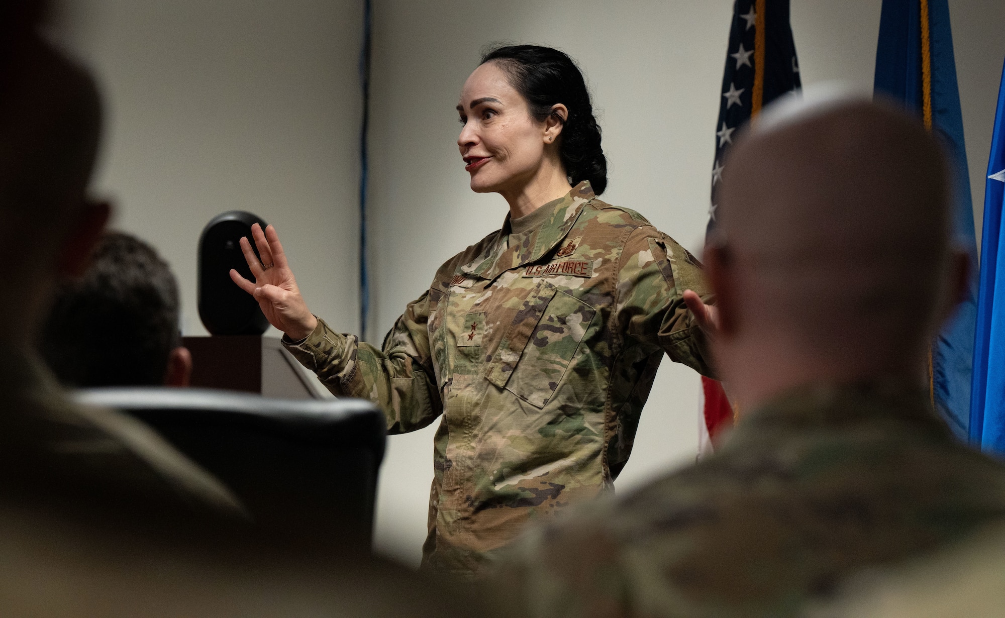 A woman in military uniform speaks to a group of people sitting down.