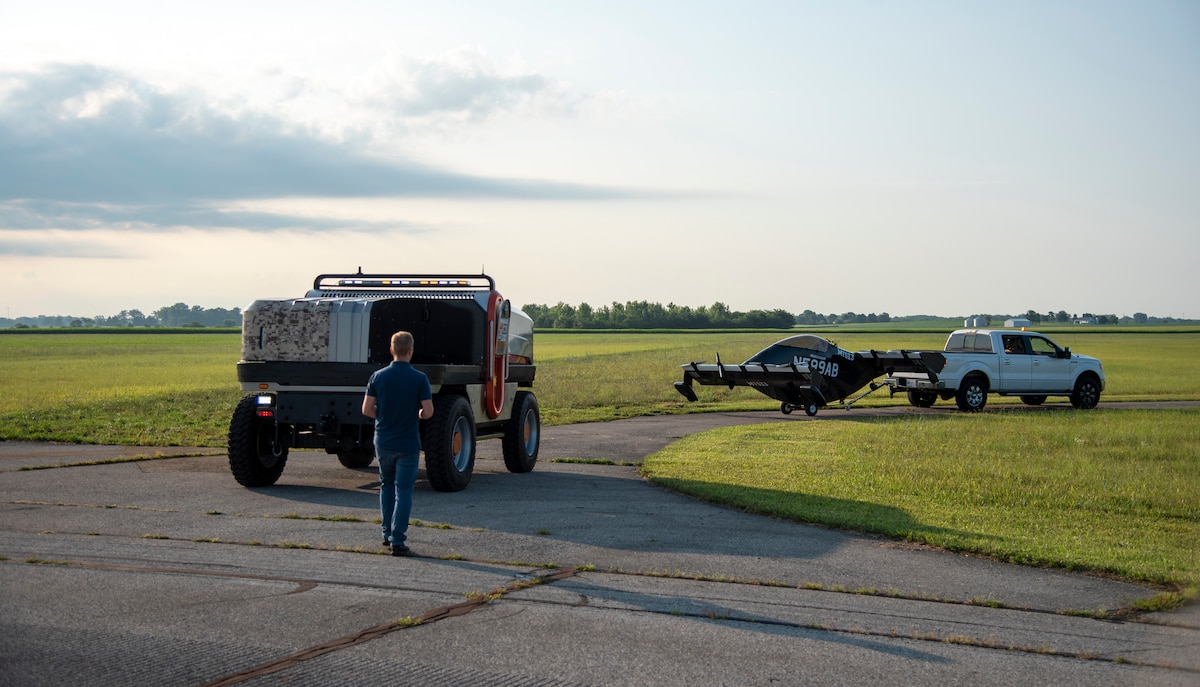 Joshua Bohun, Sinclair College associate director for advanced air mobility training, operates the remote control for the DANNAR Mobile Power Station and follows a pickup truck towing a Pivotal BlackFly electric vertical take-off and landing aircraft out to the flightline at Springfield-Beckley Airport, Ohio, July 12, 2024.