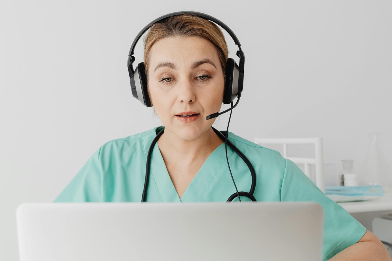 Health care provider wearing headset sitting with laptop