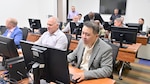 A team of professions working on computers in a classroom
