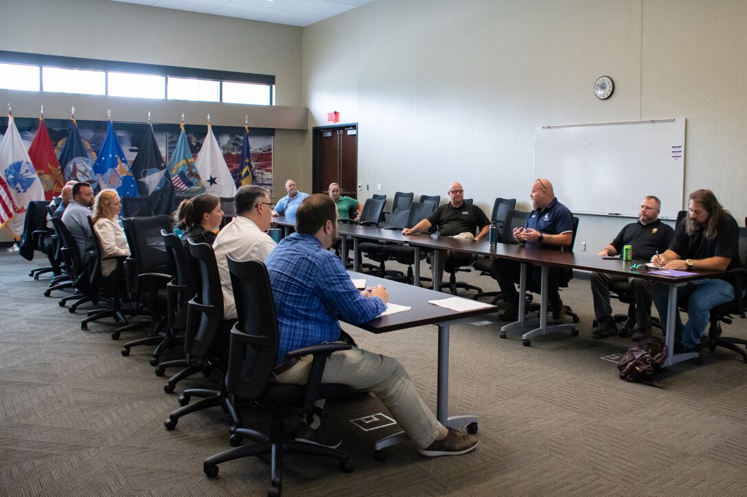 A group of people sit around a conference table speaking