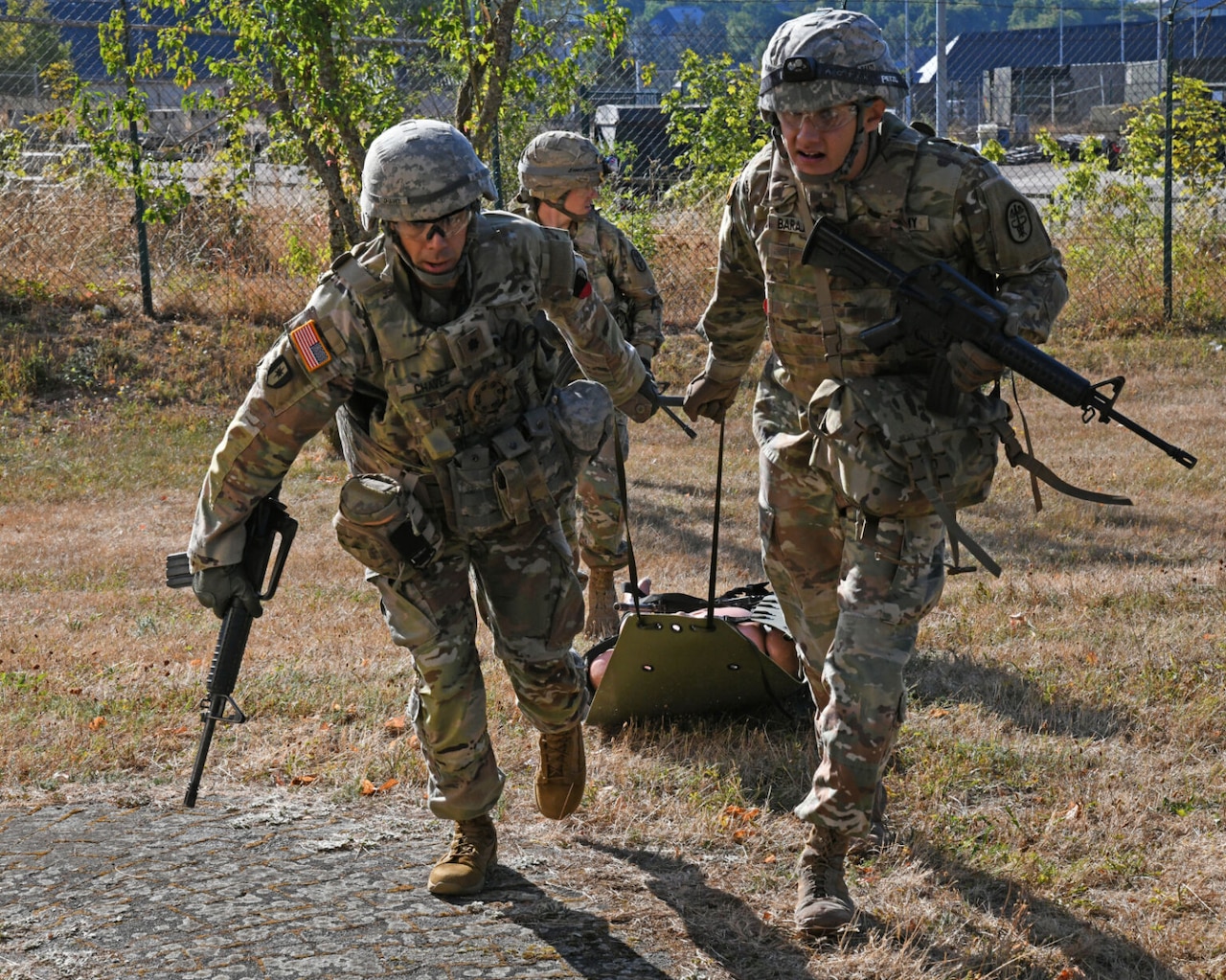 Soldiers with rifles transport simulated casualty.