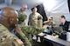 Soldiers gathered around a computer screen inside a field tent