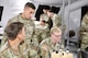 Soldiers inside a tent with the commanding general looking over their should