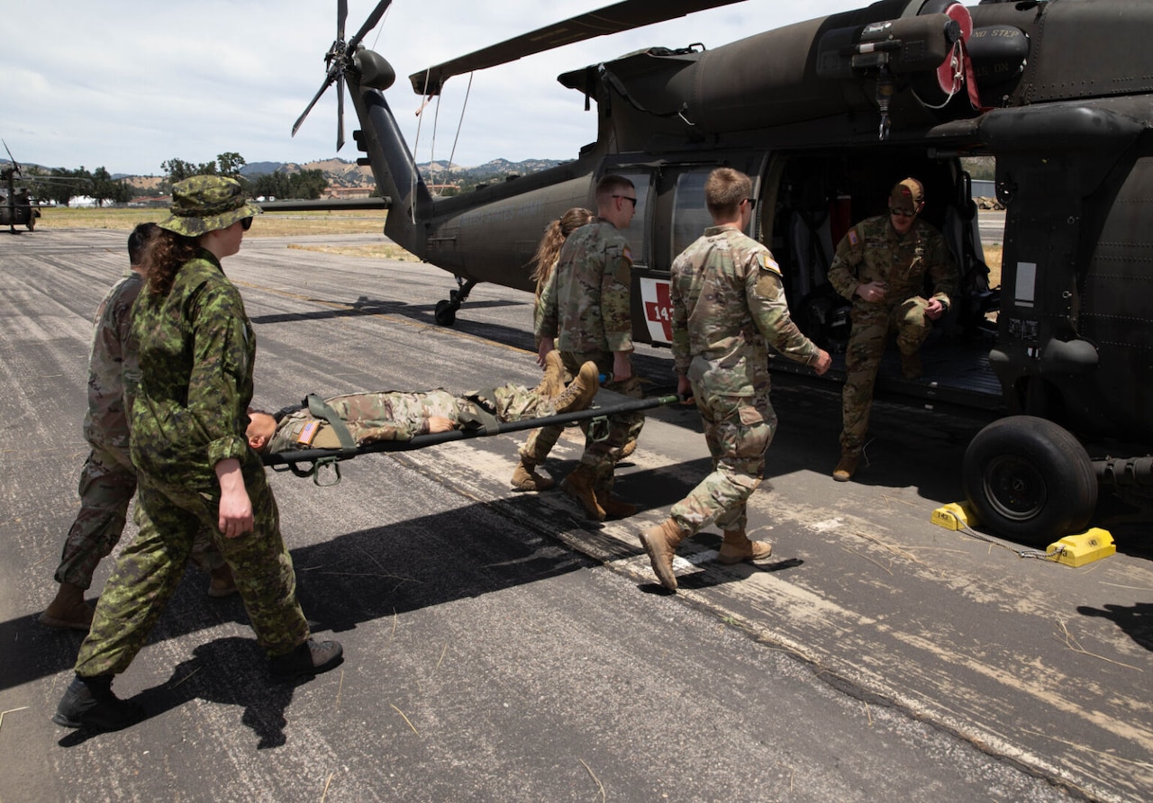 In a medical evacuation exercise, soldiers carry simulated casualty on a stretcher to a helicopter.
