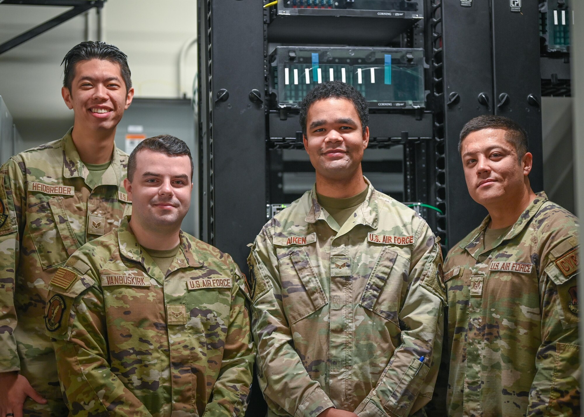 Airmen pose for a photo in a communications closet.