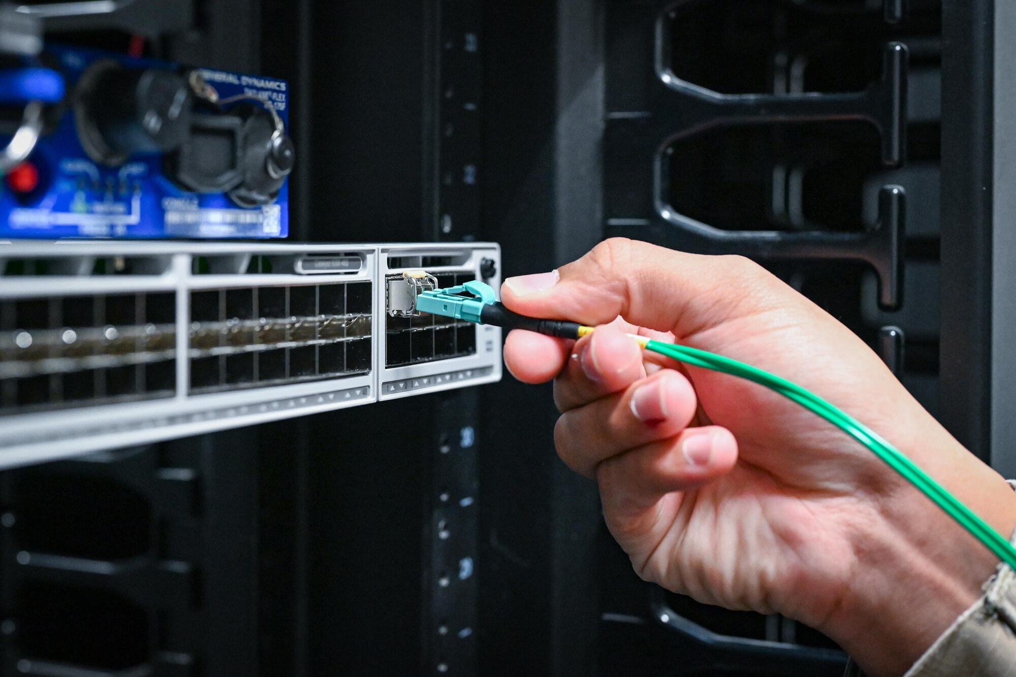 An Airman plugs a cable into a machine.