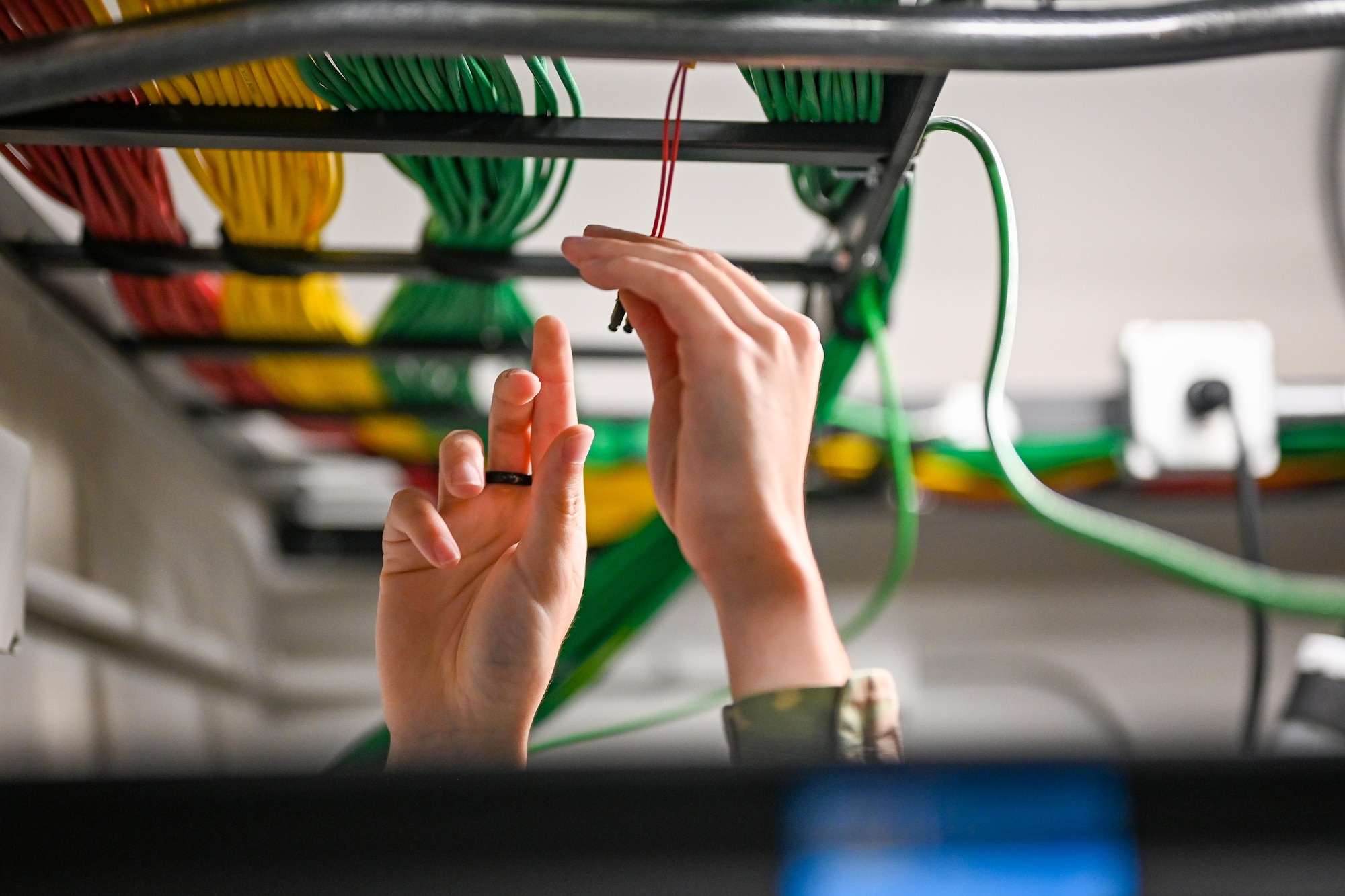 A close up of an Airman's hands organizing cables.