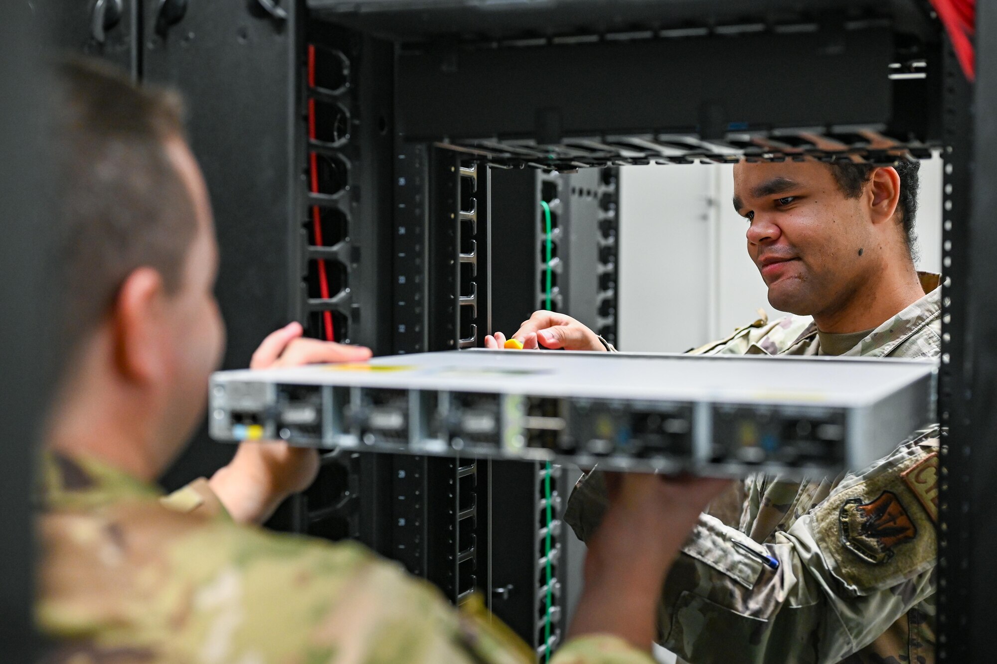 Two Airmen install network equipment.
