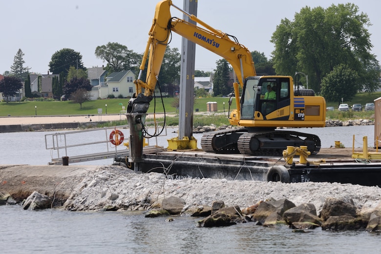 Construction equipment breaks apart concrete breakwater in Algoma Harbor so that a new wall can be reconstructed.