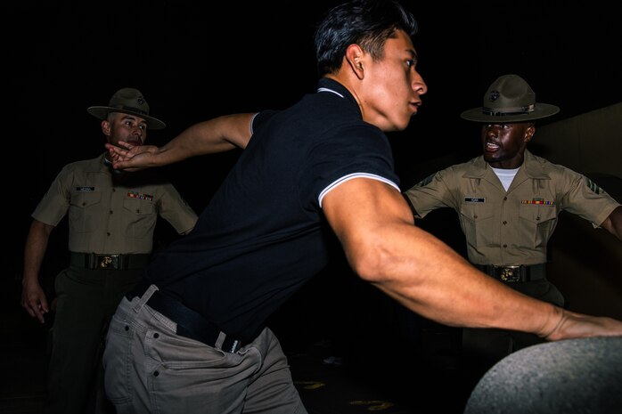 U.S. Marine Corps Sgt. Emmanuel Medina, left, and Sgt. Sharif M. Adan, both drill instructors with Receiving Company, Support Battalion, direct new recruits of Echo Company, 2nd Recruit Training Battalion, off a bus during a receiving event at Marine Corps Recruit Depot San Diego, California, July 22, 2024. During the receiving process, recruits are checked for contraband, given haircuts, make a scripted phone call home, and issued gear required for training. (U.S. Marine Corps photo by Cpl. Sarah M. Grawcock)