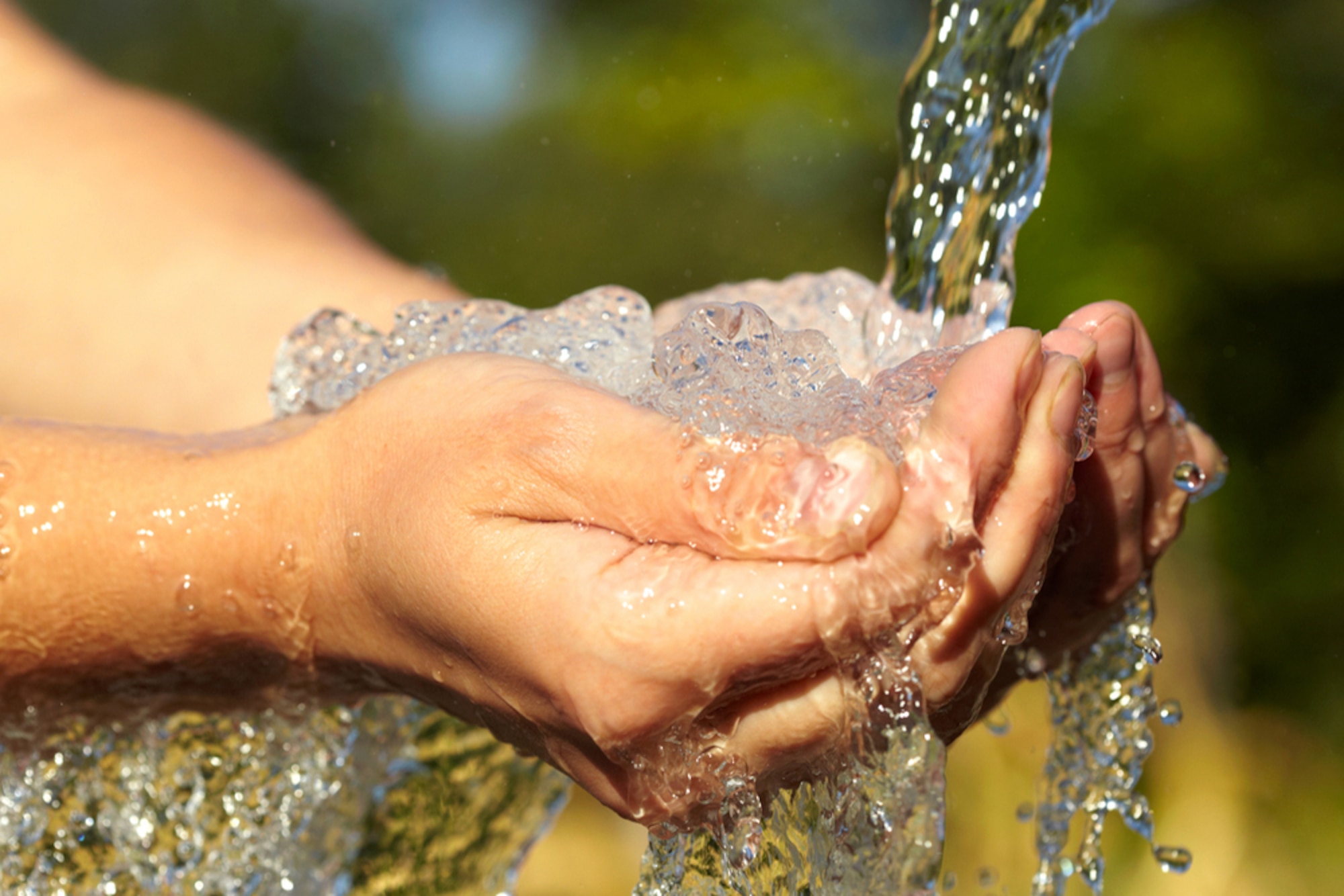 Hands under a water spigot with water washing over