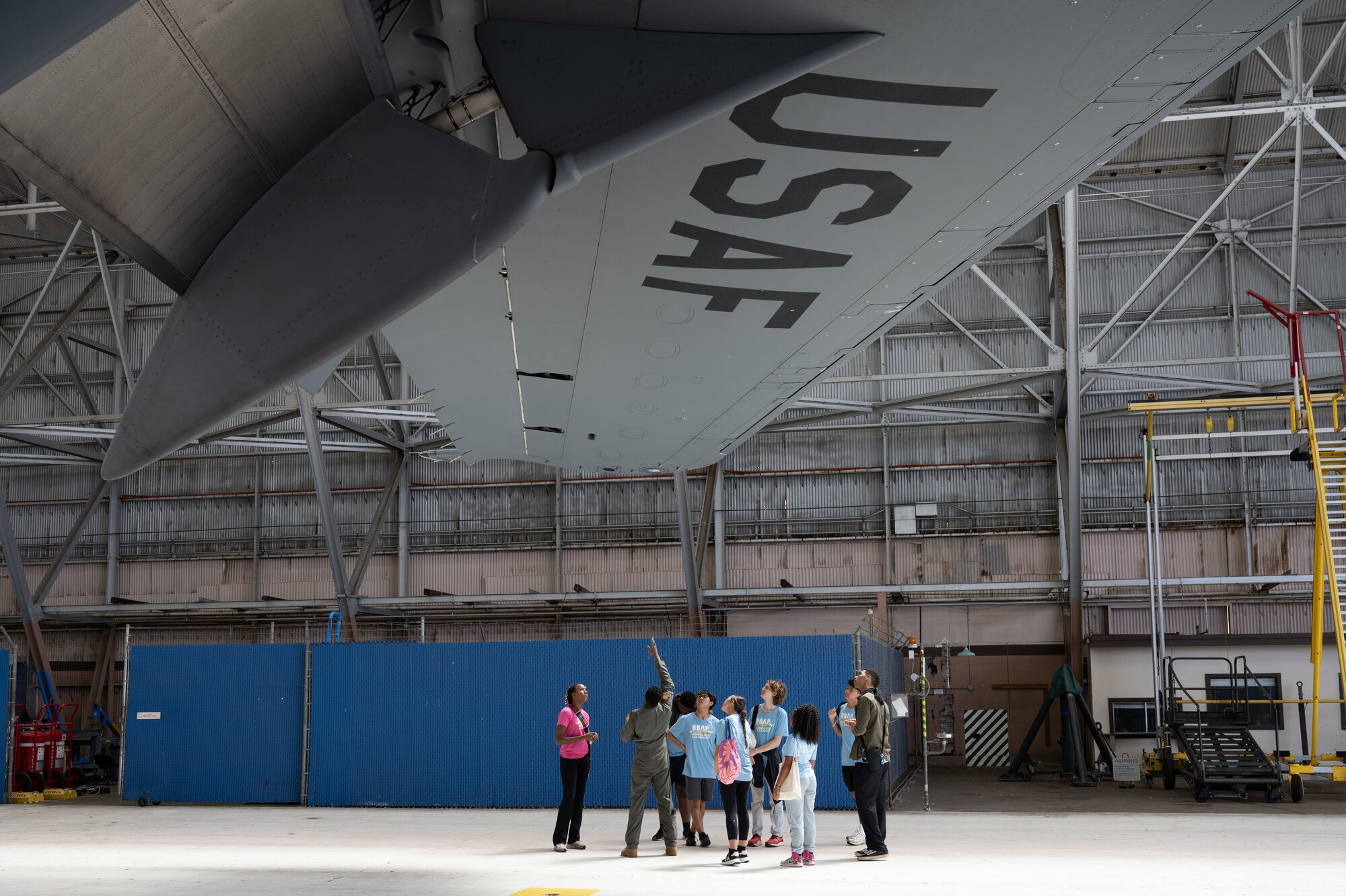 Students stand under a wing of an aircraft.