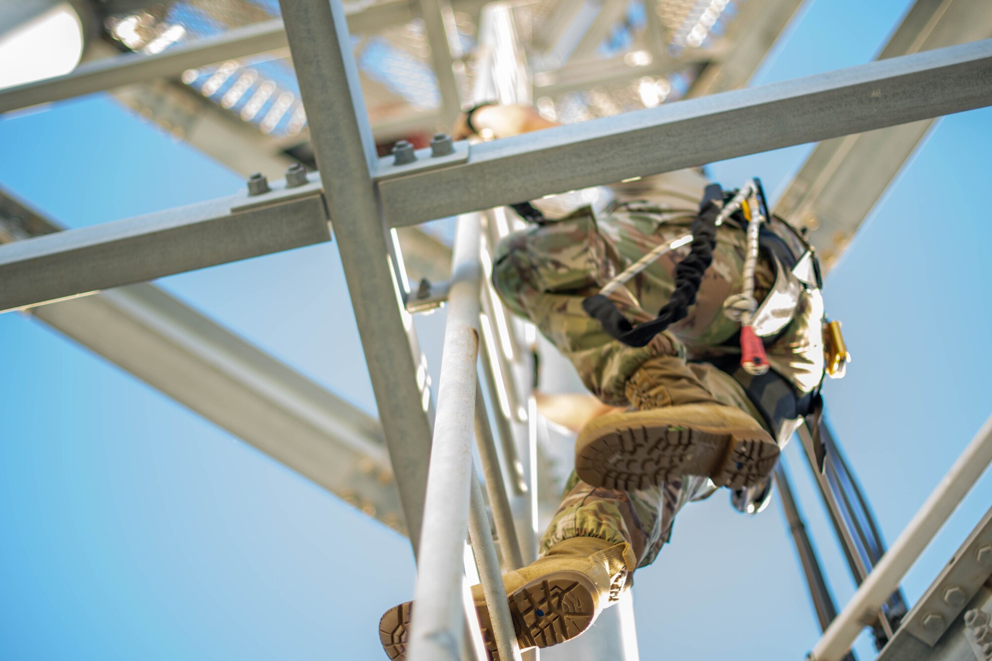 military member climbs up a training tower ladder