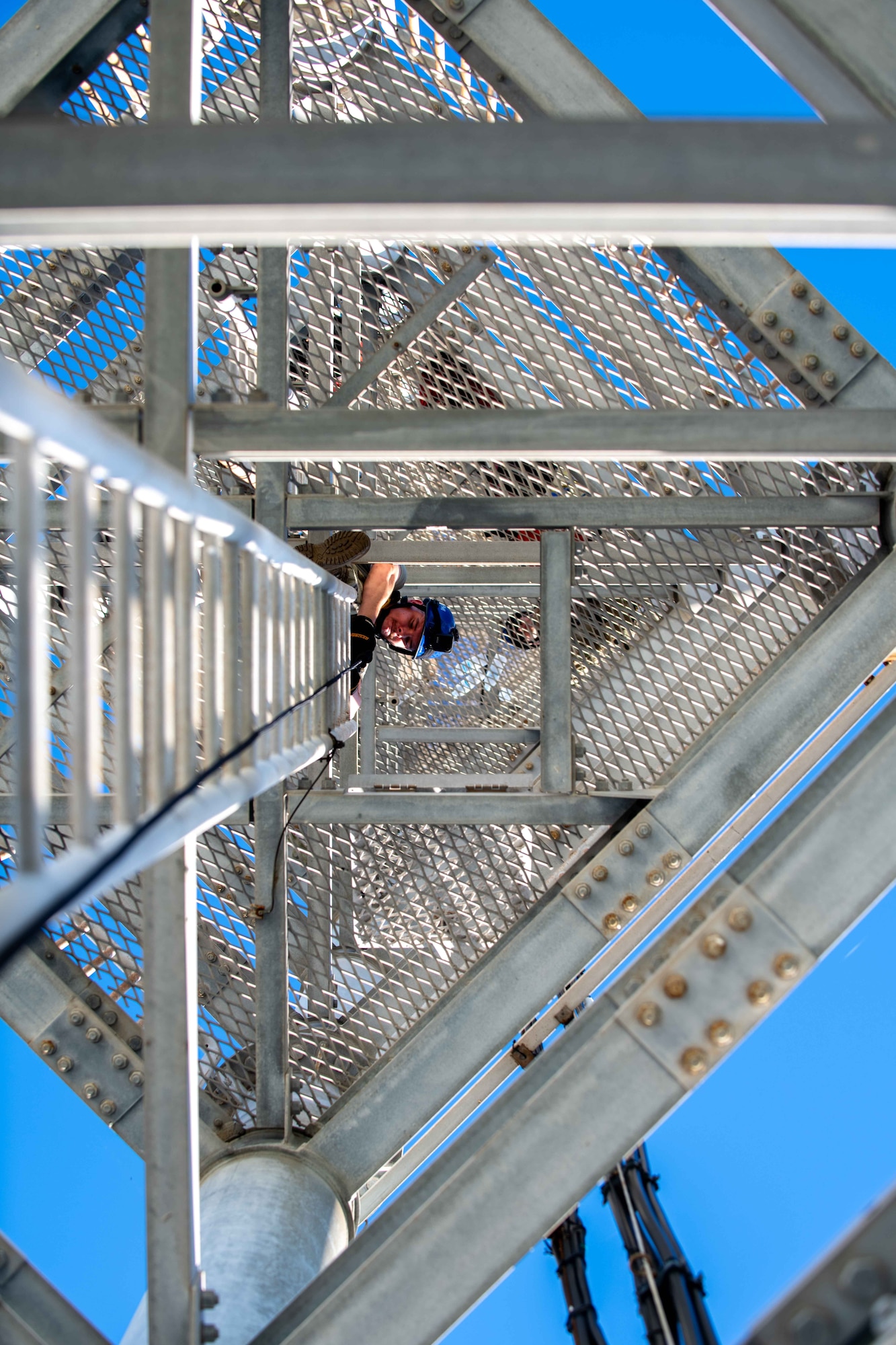 military member looks down from the top of a latter on a training tower